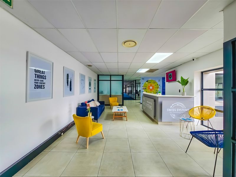 A bright and professional office reception area featuring a modern reception desk, tiled flooring, and a clean, open-plan layout with glass partitioning.