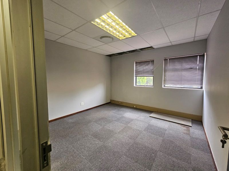 Empty office space featuring carpet tiles, venetian blinds, and a suspended ceiling with recessed lighting, currently requiring maintenance to ceiling and flooring.
