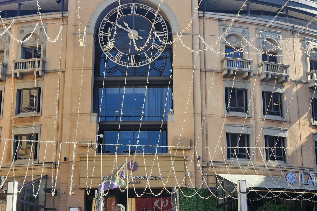 Front elevation of a commercial office building featuring a prominent decorative clock, glass windows, and architectural balconies overlooking the square.