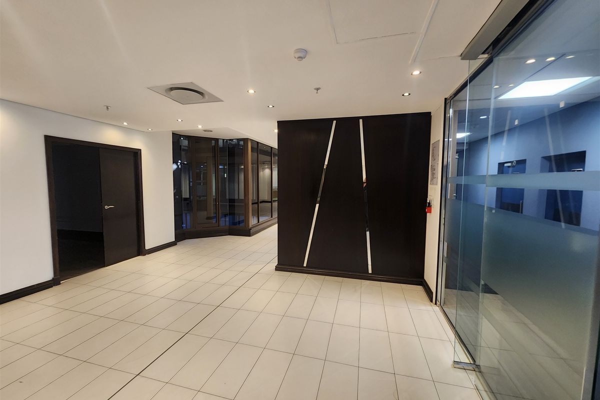A modern, vacant office lobby or reception area featuring tiled flooring, glass partitions, and a contemporary dark feature wall panel.
