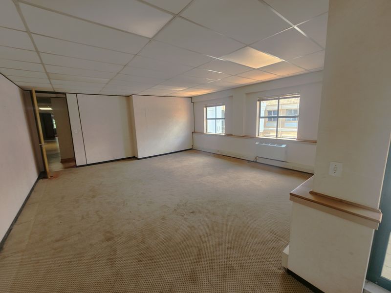 An empty office space featuring a suspended ceiling, carpeted flooring, and an integrated HVAC unit, offering a blank canvas for professional workspace customization.
