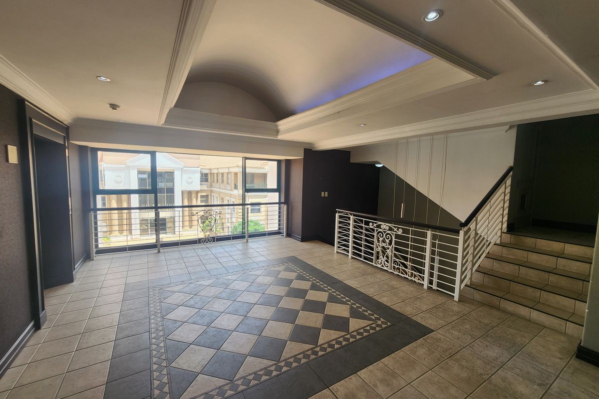 Spacious office entrance foyer featuring a vaulted ceiling, recessed lighting, decorative tiled flooring, and a wrought iron staircase railing.