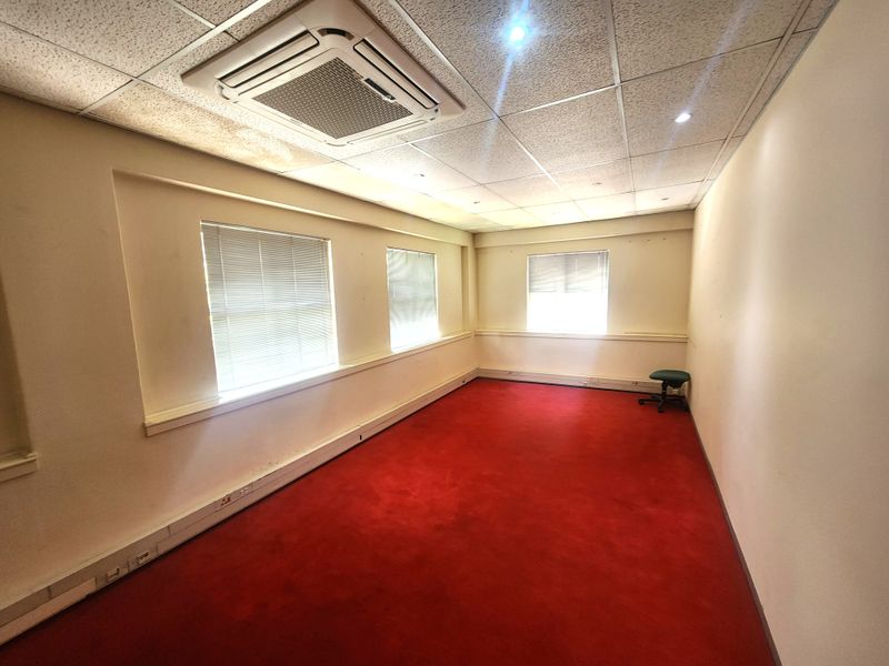Empty office space featuring a suspended ceiling with integrated air conditioning, perimeter trunking, and large windows with venetian blinds.