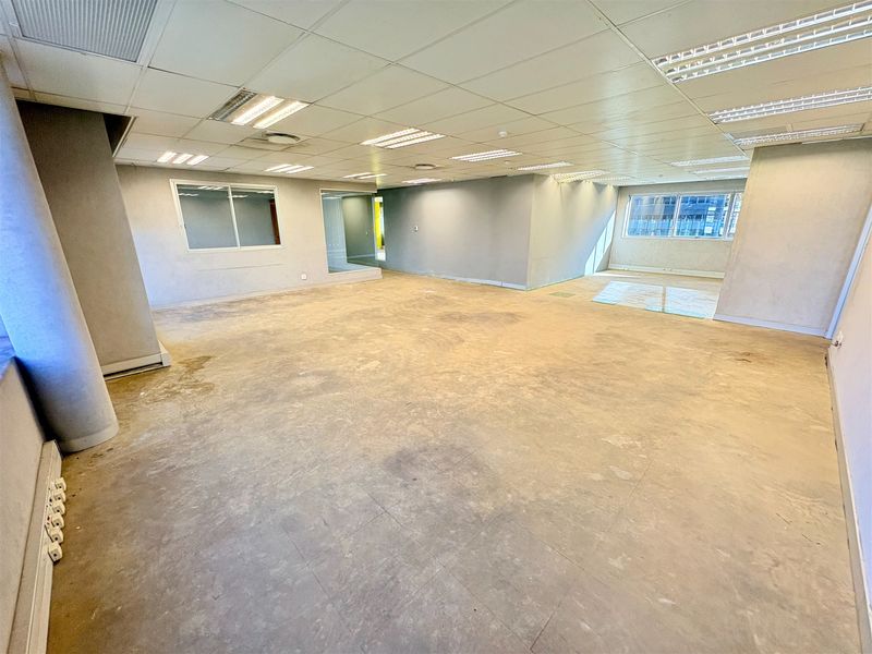 Spacious open-plan office area featuring a suspended ceiling, recessed lighting, and large windows, currently in a shell condition ready for fit-out.