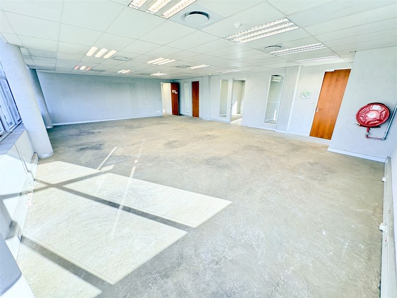 Spacious, vacant open-plan office area featuring a suspended ceiling, recessed lighting, and internal glass partitions, ready for custom fit-out.