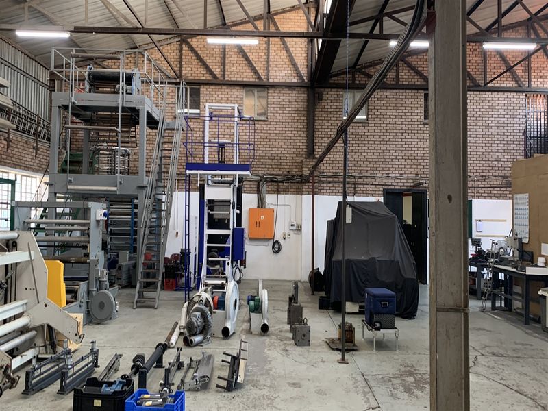 Spacious industrial utility area featuring exposed steel roof trusses, brick walls, concrete flooring, and integrated industrial machinery infrastructure.