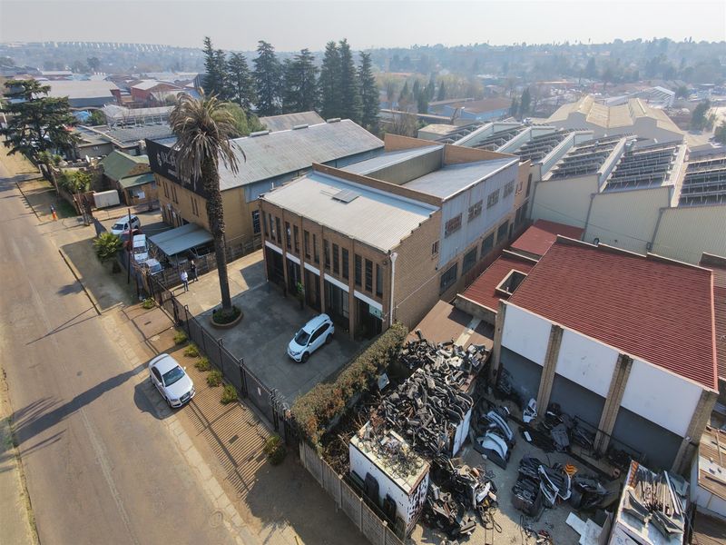 Aerial view of an industrial property featuring multiple warehouse buildings, concrete yard space, and perimeter fencing in an established commercial area.