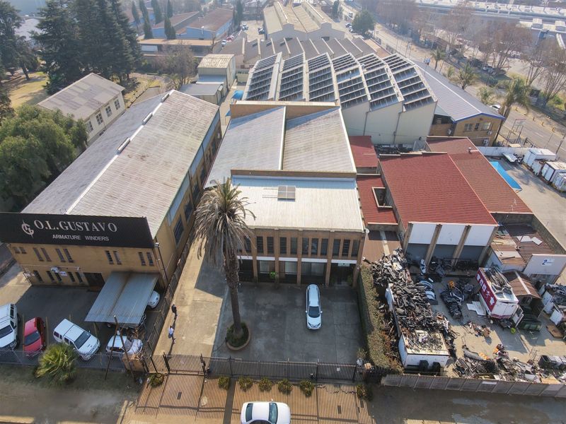 Aerial view of an industrial property complex featuring multiple warehouse buildings, solar panel installations, and a paved yard area.
