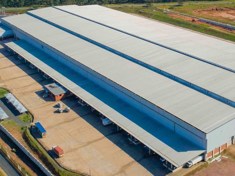 Aerial view of a large industrial warehouse facility featuring extensive metal roofing, multiple loading docks, and a spacious concrete yard for logistics operations.