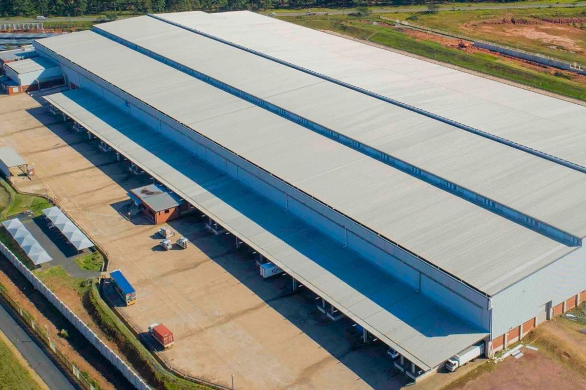 Aerial view of a large industrial warehouse facility featuring extensive metal roofing, multiple loading docks, and a spacious concrete yard for logistics operations.