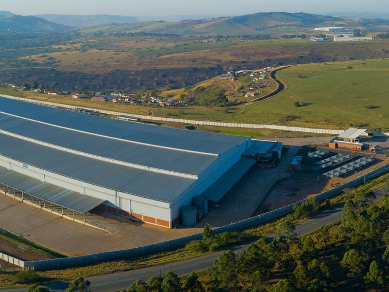 Aerial view of a large-scale industrial warehouse facility featuring extensive roofing, paved loading areas, and secure perimeter fencing in a rural setting.