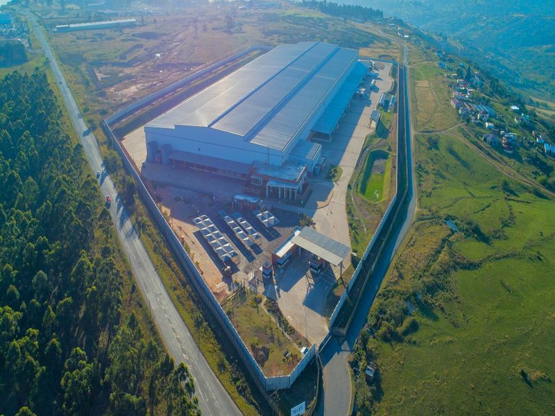 Aerial view of a large industrial warehouse facility featuring a secure perimeter, gated entrance, loading bays, and extensive paved yard space.