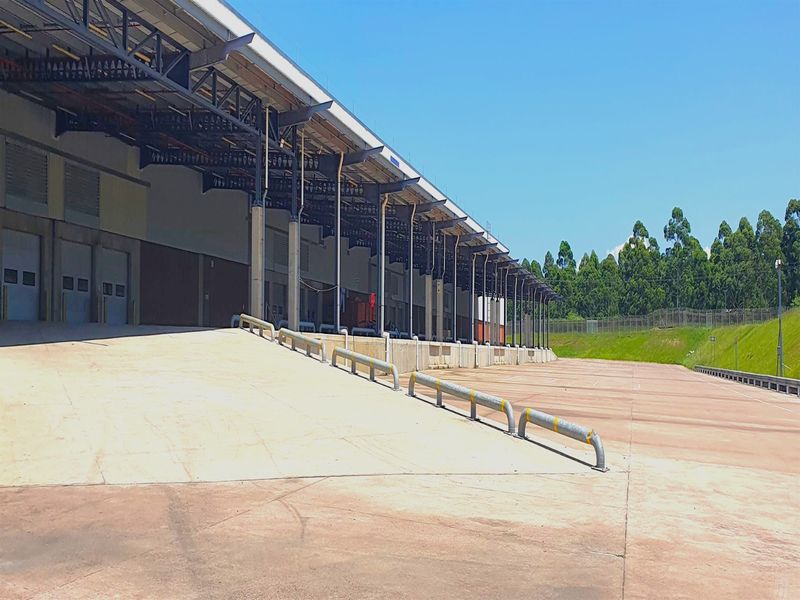 Industrial loading bay area featuring a concrete ramp, steel truss roof structure, and multiple roller shutter doors for efficient logistics operations.