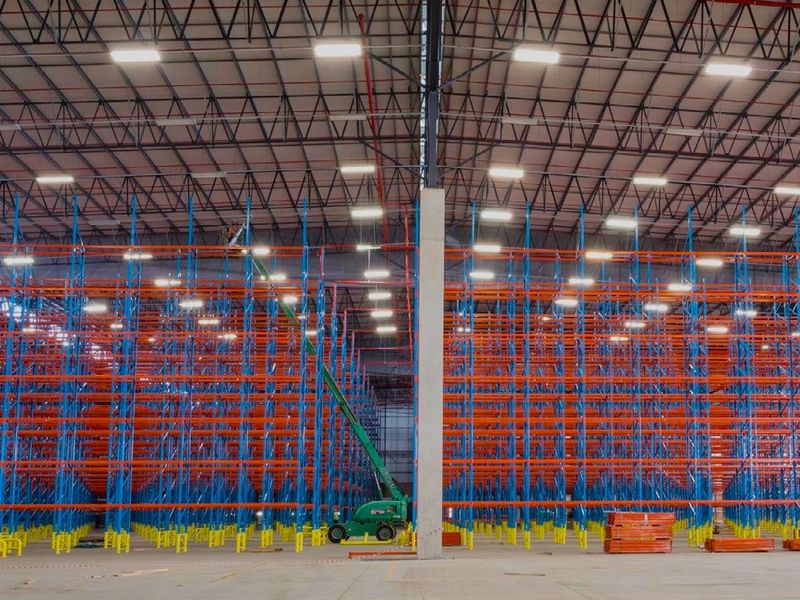 Expansive industrial warehouse space featuring high-clearance ceilings, extensive steel racking systems, polished concrete flooring, and modern overhead lighting.