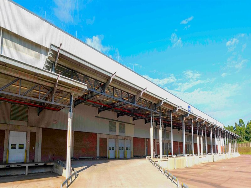 Industrial warehouse exterior featuring multiple loading docks, a large covered loading apron, and exposed steel structural elements.