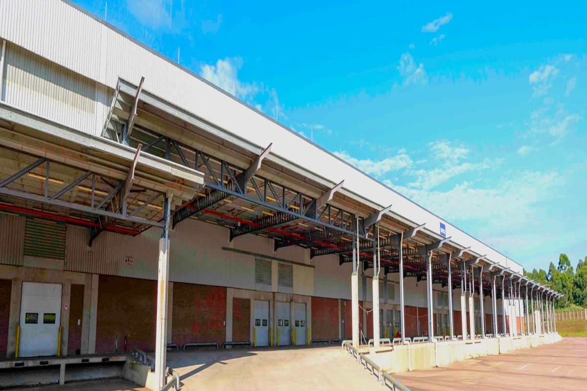 Industrial warehouse exterior featuring multiple loading docks, a large covered loading apron, and exposed steel structural elements.