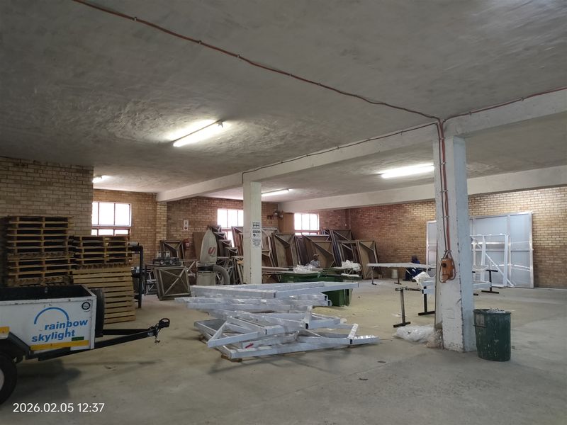 Spacious industrial utility area featuring exposed brick walls, concrete flooring, and structural support columns, suitable for manufacturing or storage operations.