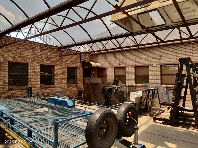 Industrial utility space featuring exposed brick walls, concrete flooring, and a large arched polycarbonate roof structure.