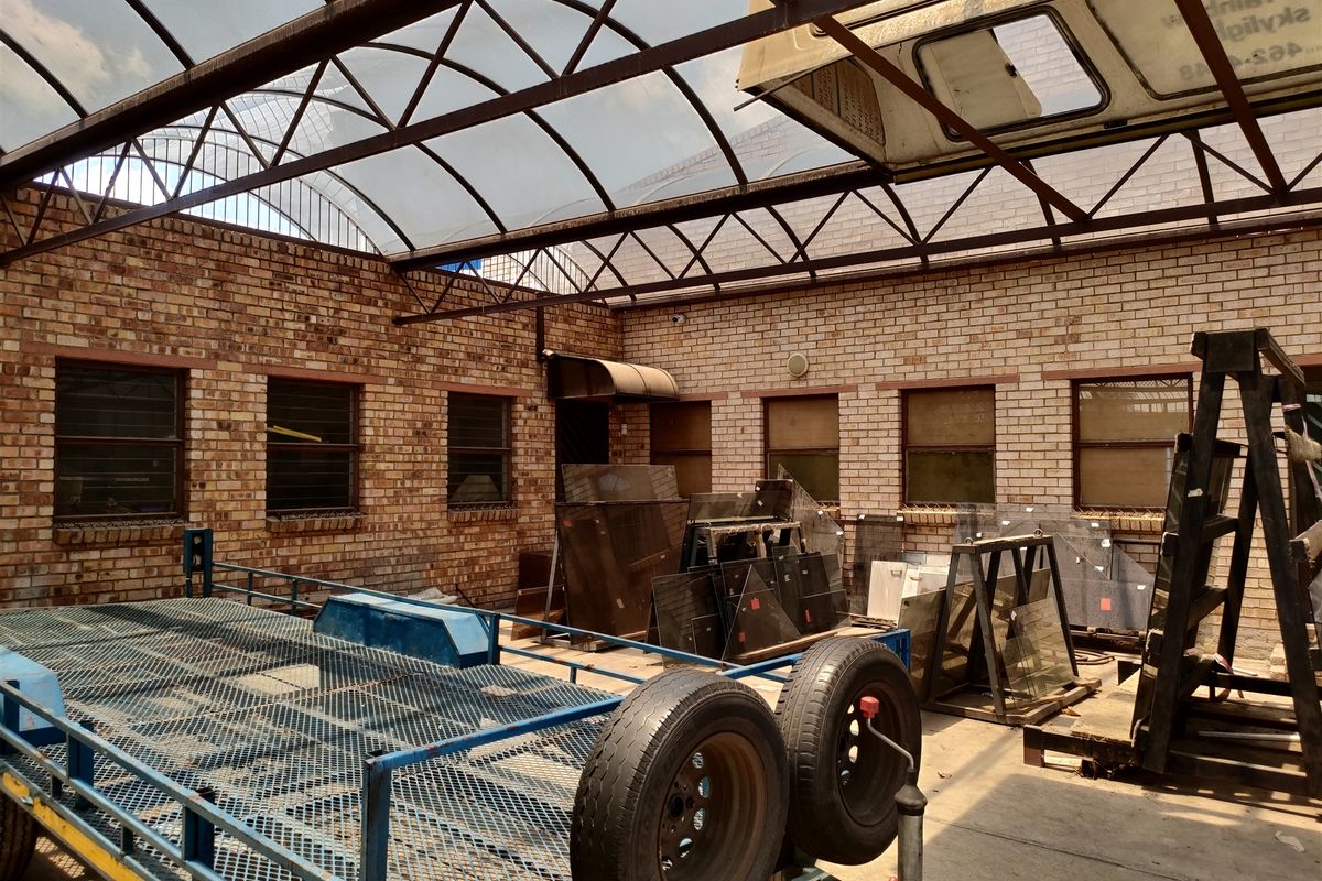 Industrial utility space featuring exposed brick walls, concrete flooring, and a large arched polycarbonate roof structure.