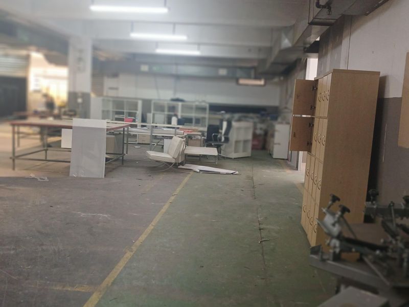 Spacious industrial warehouse area featuring high ceilings, exposed ductwork, and durable concrete flooring, suitable for manufacturing or storage operations.