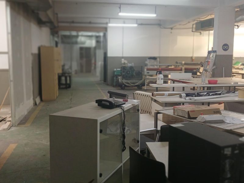 An industrial workspace featuring exposed ceiling lighting, concrete flooring, and open-plan layout suitable for manufacturing or storage operations.