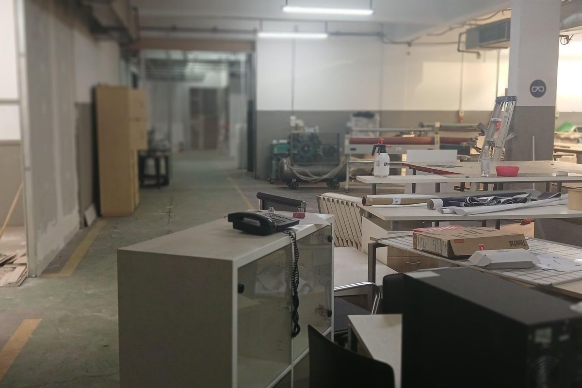 An industrial workspace featuring exposed ceiling lighting, concrete flooring, and open-plan layout suitable for manufacturing or storage operations.