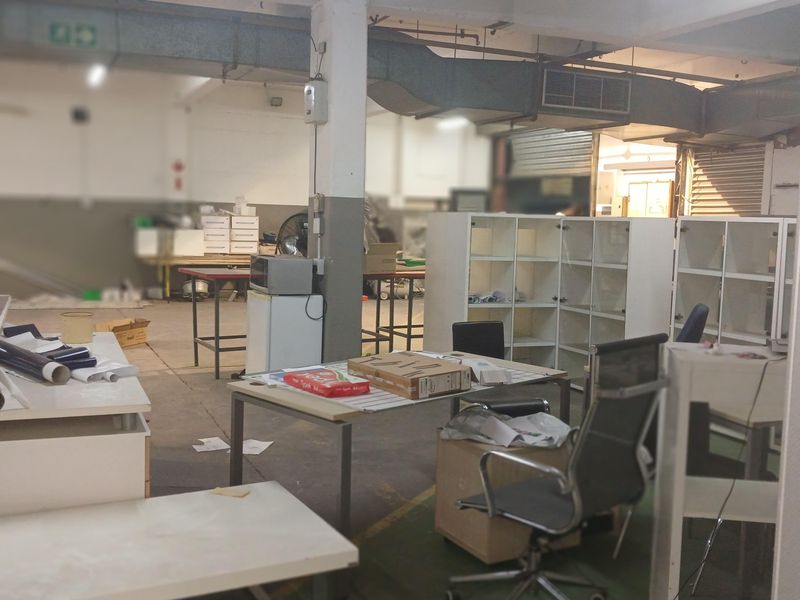 Open-plan industrial warehouse space featuring exposed ceiling ducting, concrete flooring, and functional structural columns, suitable for workshop or storage use.
