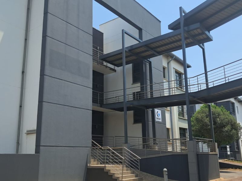 Modern office building exterior featuring contemporary architectural design, elevated walkways, and paved access stairs.