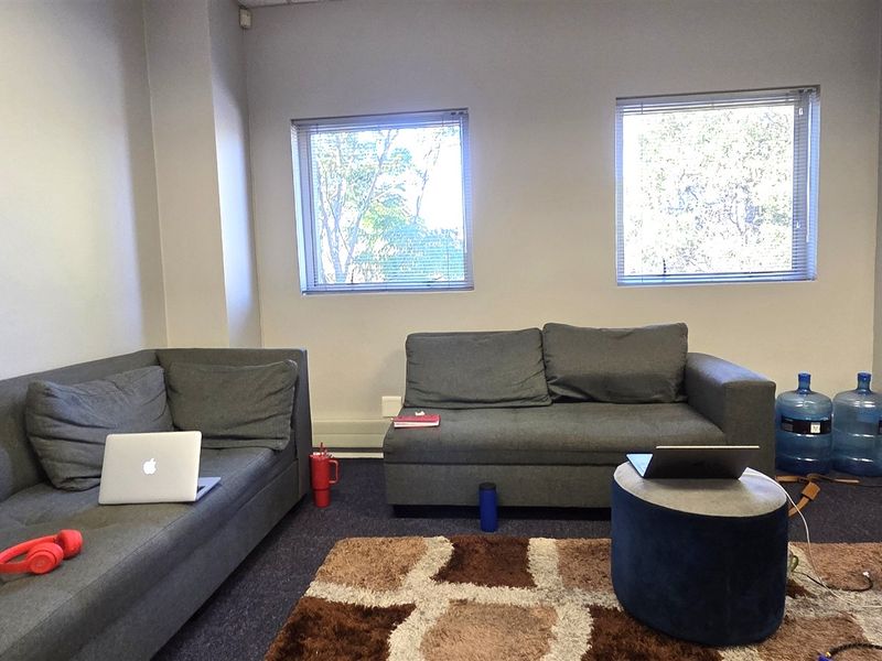 A functional office space featuring carpeted flooring and dual windows with horizontal blinds, providing a neutral environment suitable for a professional workspace.