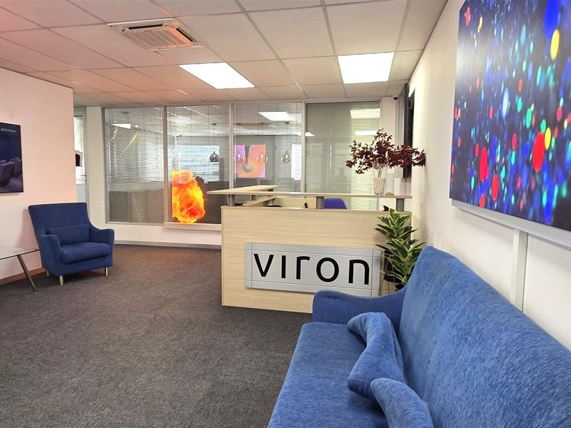 Professional office reception area featuring a branded reception desk, glass partitioning, and a clean, modern layout with carpeted flooring.