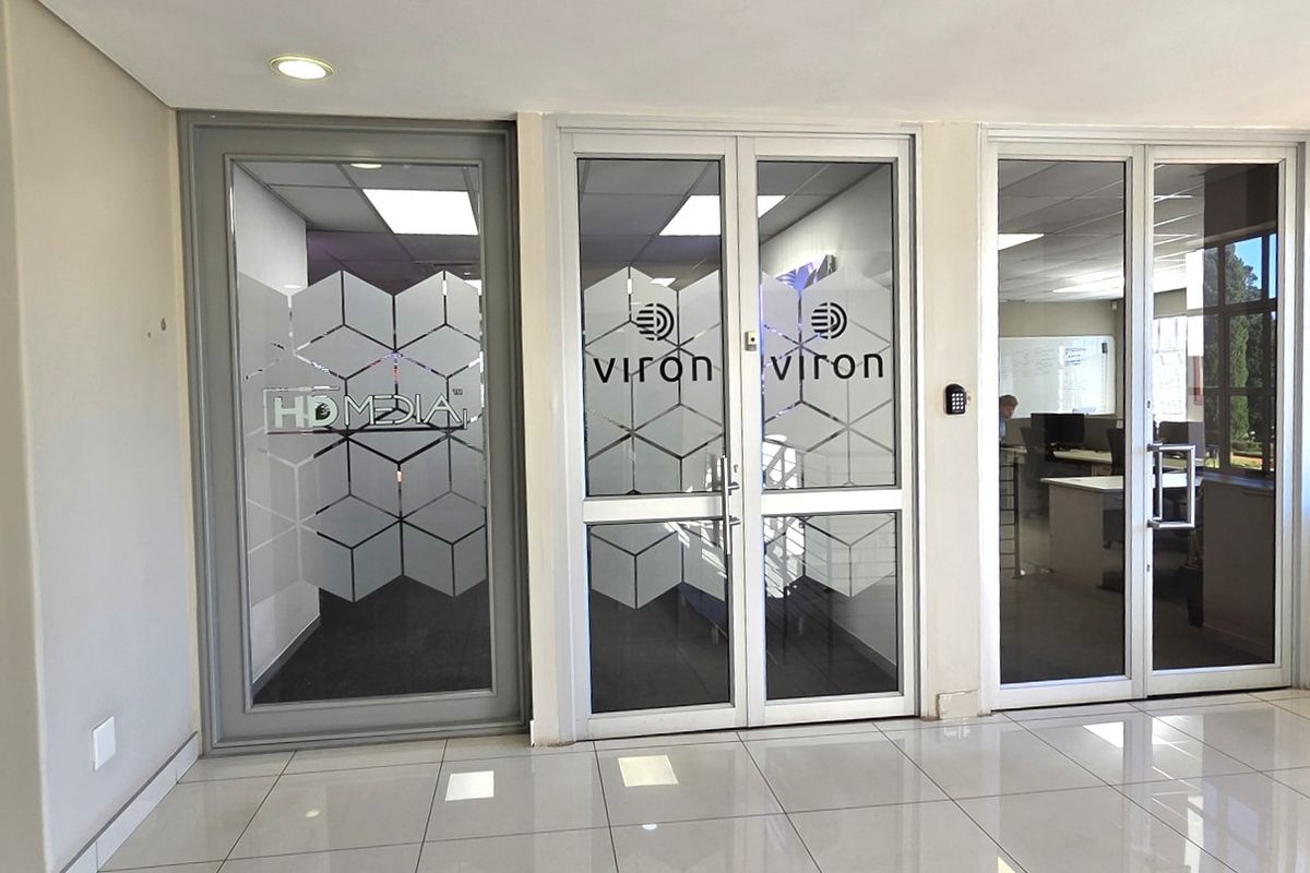 A bright office entrance lobby featuring modern glass partition doors, tiled flooring, and integrated access control systems.