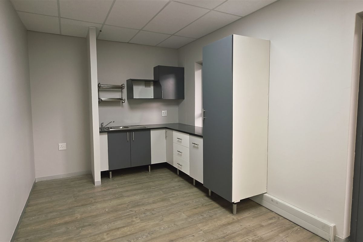 A clean, modern kitchenette area featuring built-in cabinetry, a stainless steel sink, and direct access to an outdoor patio space.