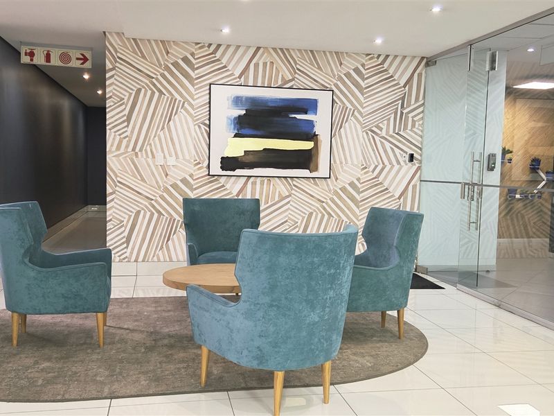 A modern office reception or waiting area featuring polished tile flooring, decorative wall paneling, and a glass partition wall.