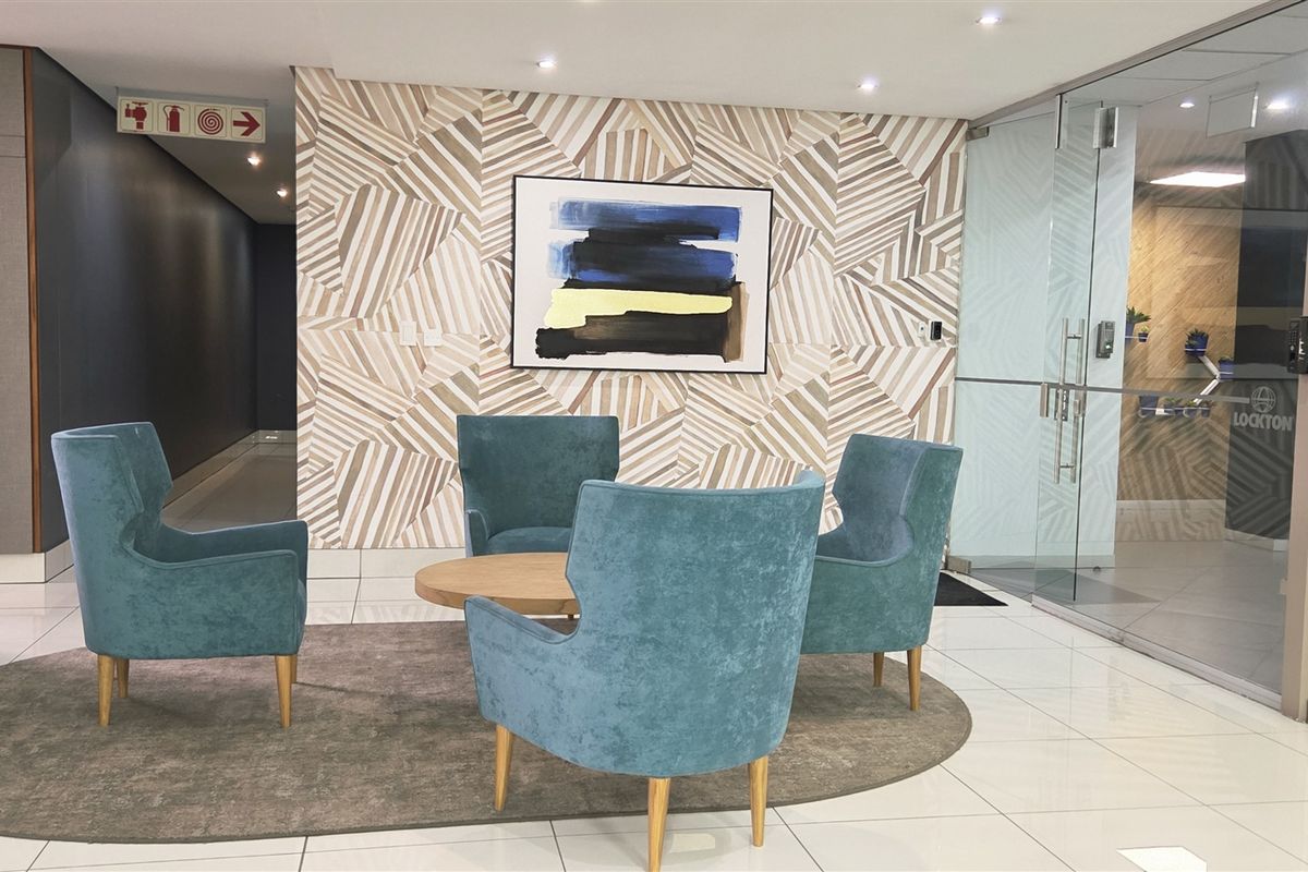 A modern office reception or waiting area featuring polished tile flooring, decorative wall paneling, and a glass partition wall.