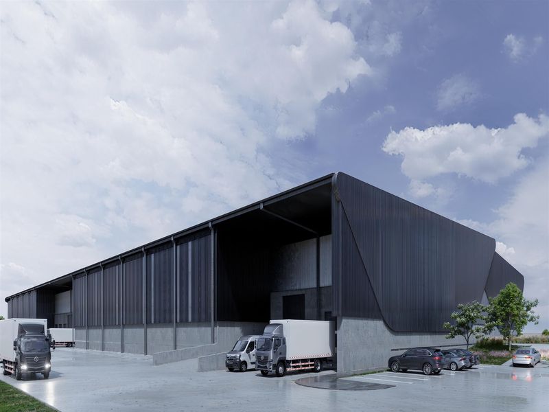 Modern industrial warehouse facility featuring extensive metal cladding, a large covered loading bay, and a spacious concrete hardstand area for logistics operations.