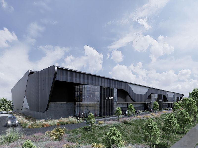 Modern industrial warehouse facility featuring sleek black metal cladding, expansive glass facade, and professional landscaping.