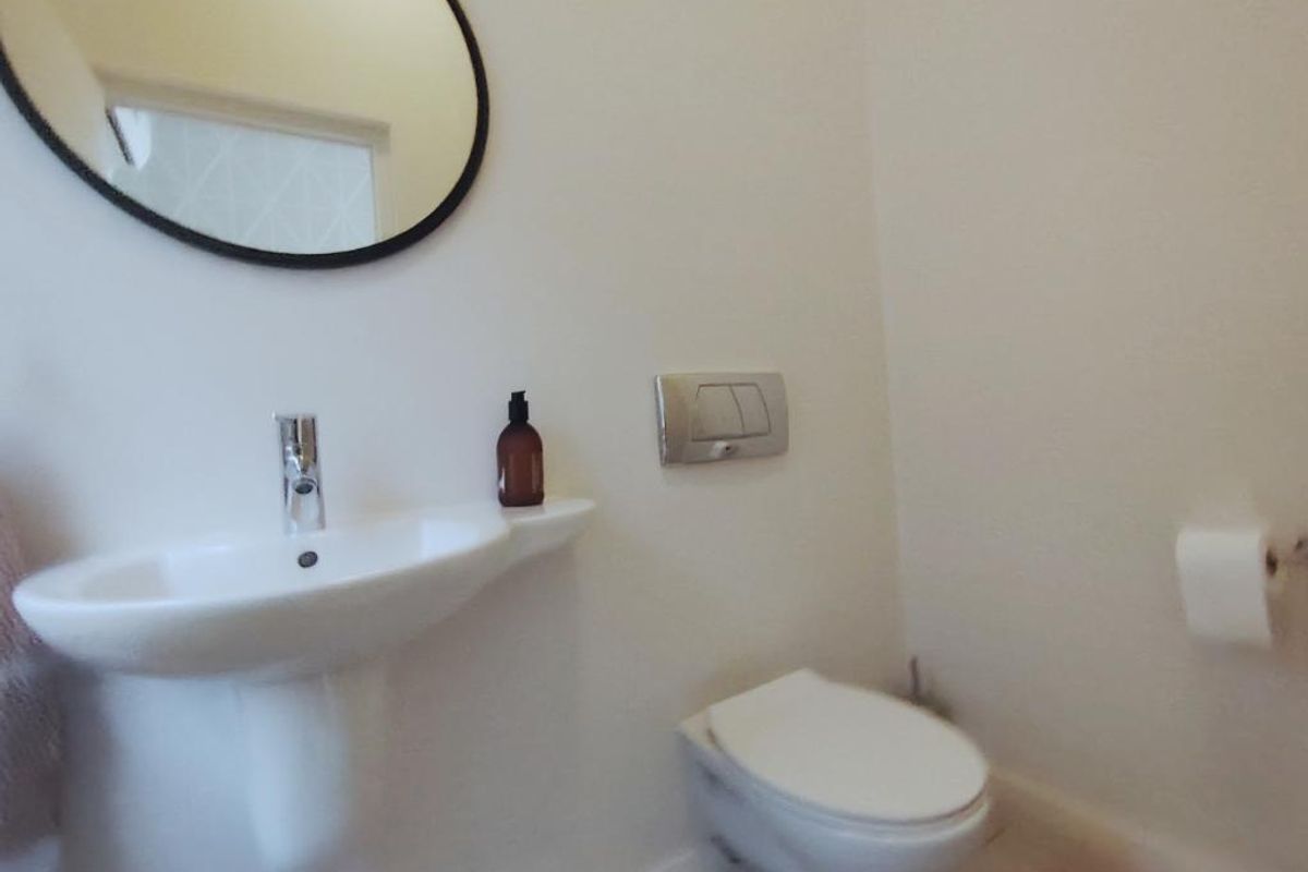 A clean and modern guest bathroom featuring a wall-mounted toilet with a concealed cistern and a pedestal basin.