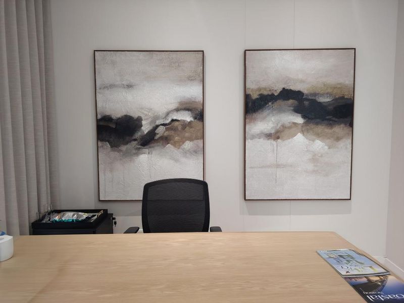 A professional office space featuring a clean, minimalist aesthetic with neutral wall tones and integrated wall-mounted art.