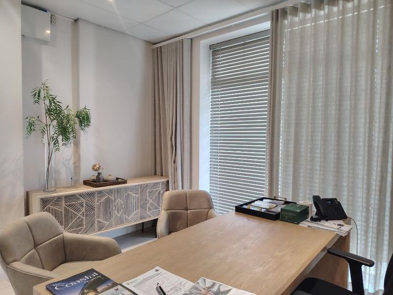 A professional office space featuring large windows with integrated blinds, neutral wall finishes, and a clean, modern aesthetic suitable for a business environment.