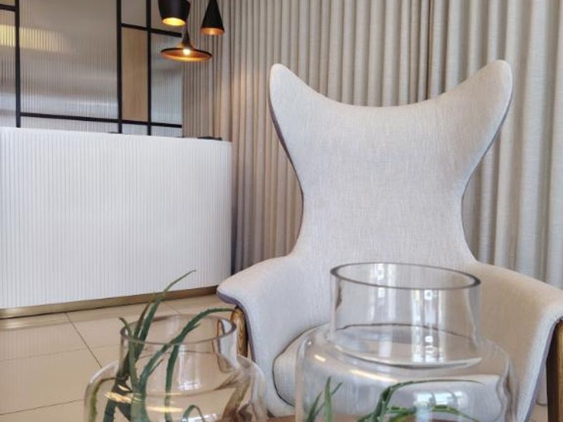 Modern office reception area featuring a sleek white counter, contemporary pendant lighting, and floor-to-ceiling curtains, creating a professional and welcoming atmosphere.