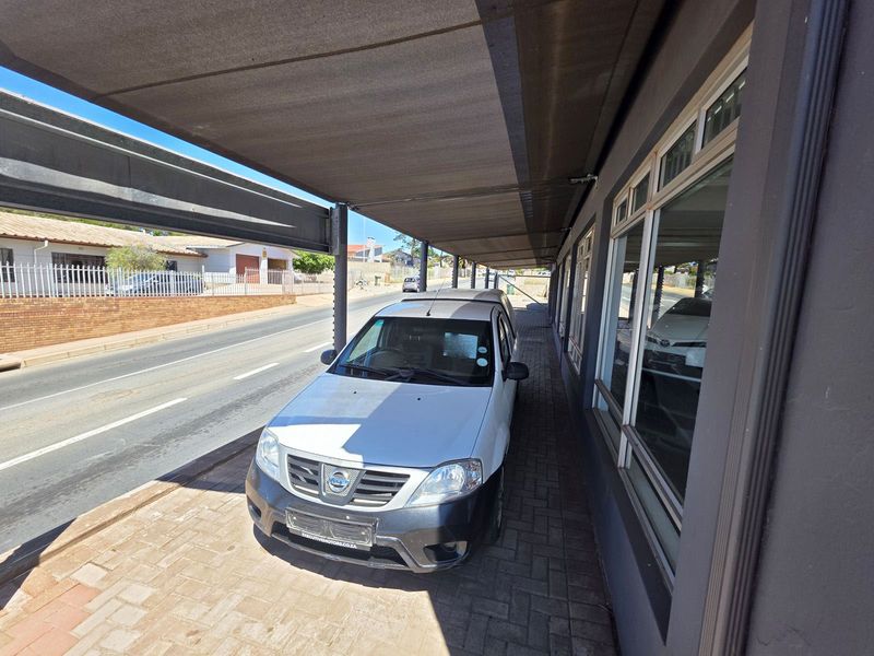 Front exterior view of the retail property featuring a paved walkway, large display windows, and a protective shade cloth awning.