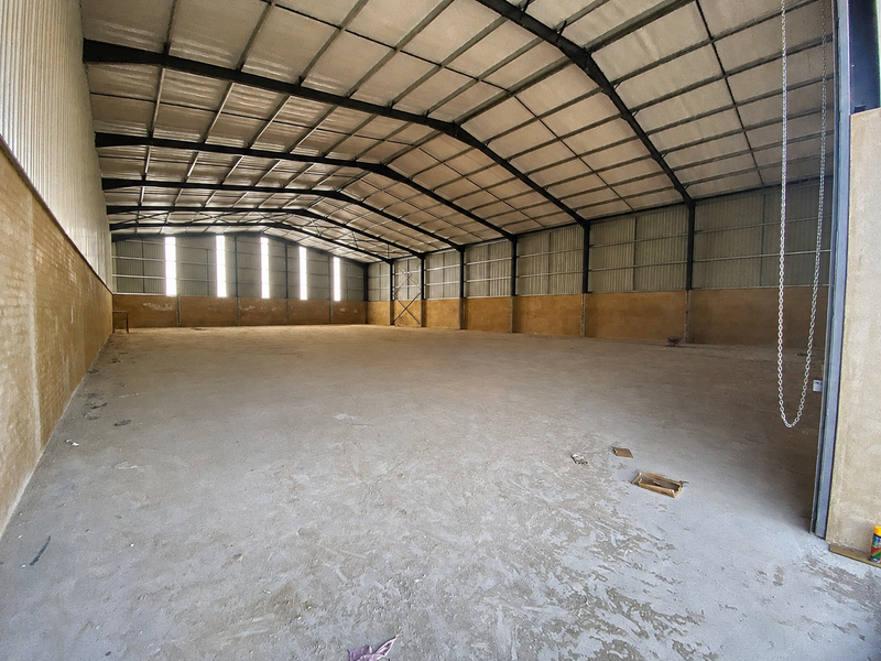 Spacious industrial warehouse unit featuring a high-clearance steel portal frame, corrugated metal roofing, and durable concrete flooring, suitable for storage or manufacturing operations.