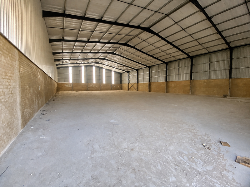 Spacious industrial warehouse featuring a high-clearance steel portal frame, concrete flooring, and durable brick and metal wall construction.