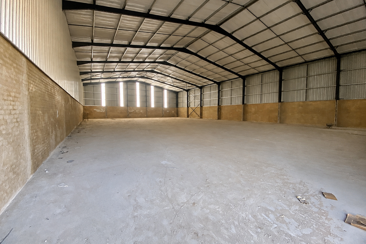 Spacious industrial warehouse featuring a high-clearance steel portal frame, concrete flooring, and durable brick and metal wall construction.