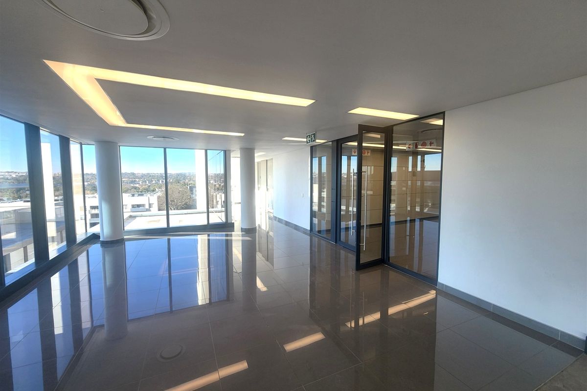 Modern, open-plan office space featuring polished floor tiles, recessed ceiling lighting, and floor-to-ceiling glass partitions with expansive views.