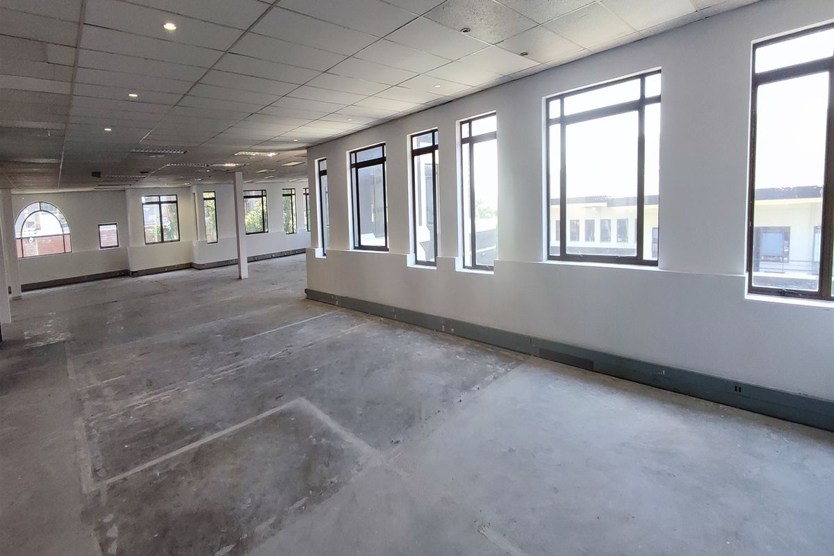 Spacious open-plan office area featuring a suspended ceiling, recessed lighting, and large windows providing ample natural light, currently in a shell condition.