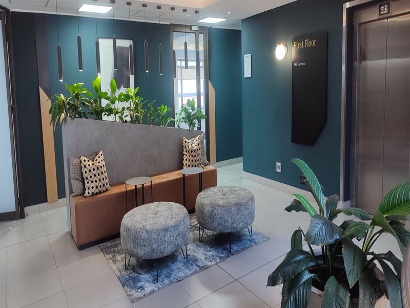 Modern office lobby area featuring a contemporary waiting space, elevator access, and professional dark teal wall finishes with integrated signage.