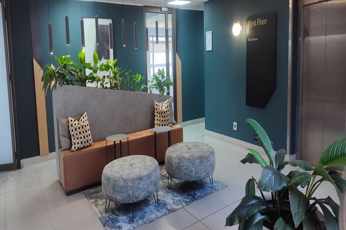 Modern office lobby area featuring a contemporary waiting space, elevator access, and professional dark teal wall finishes with integrated signage.