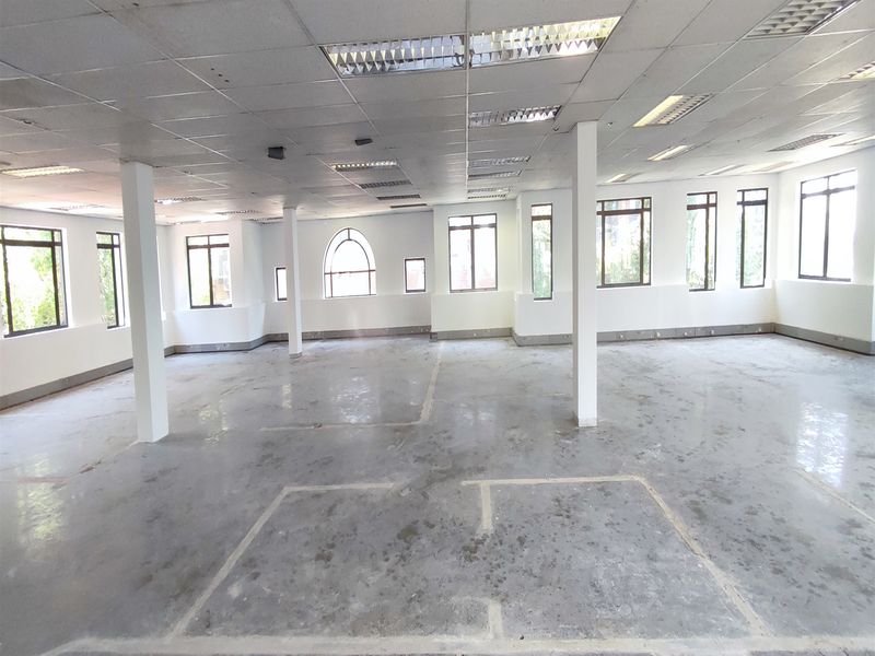 Spacious open-plan office area featuring large windows, structural columns, and a suspended ceiling, currently in a shell condition ready for fit-out.