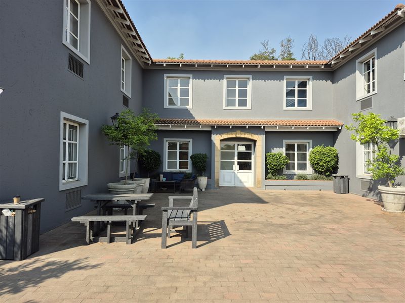 A well-maintained paved courtyard area featuring a U-shaped building layout with classic multi-pane windows and terracotta roof tiles.